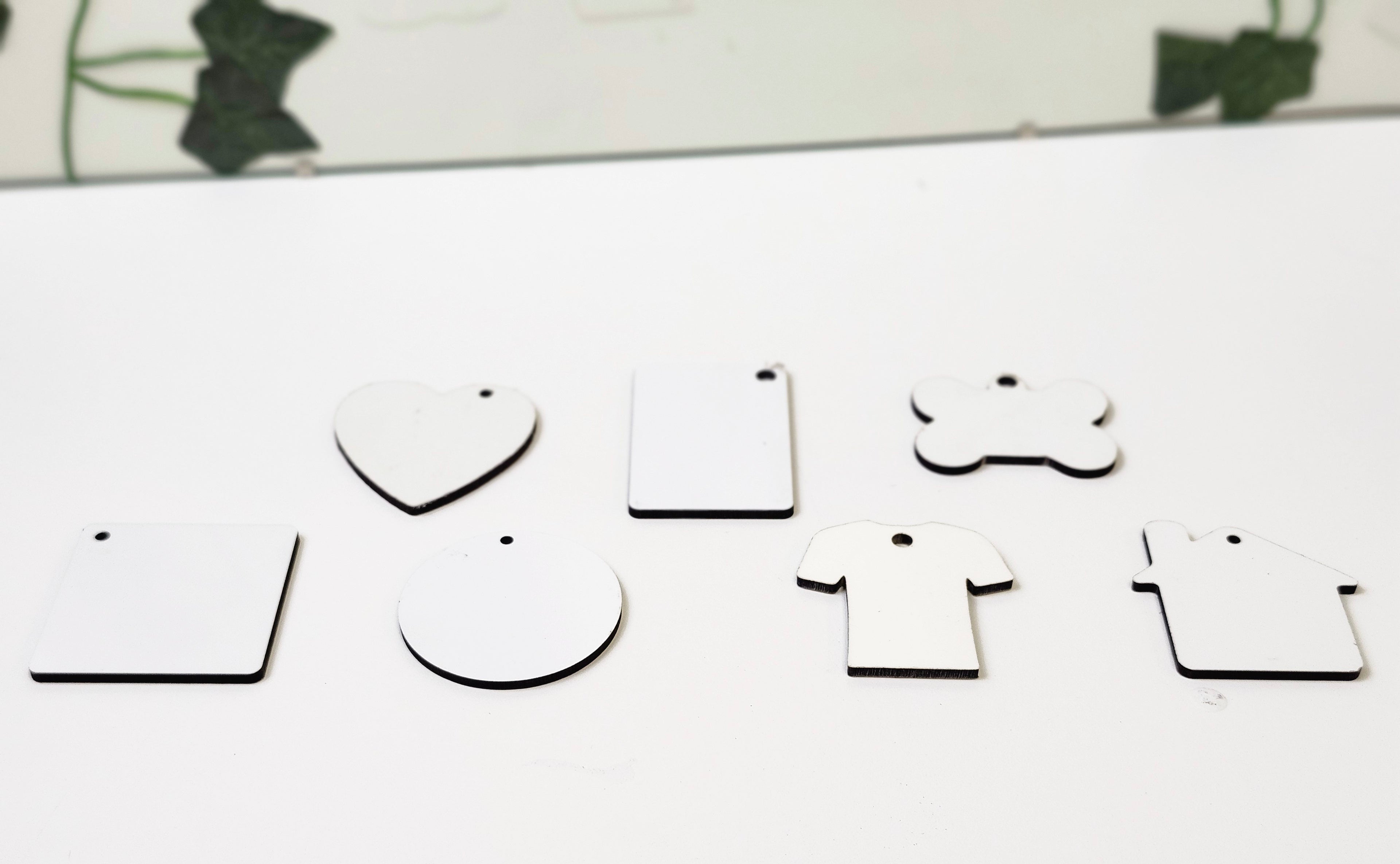 White MDF Keychain that can be customized with sublimation by Jennnayyy's.  The shapes are circle, heart, rectangle, tshirt, and square, bone and home.